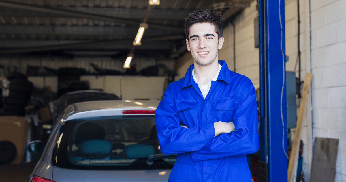 young person in blue overalls training to become a car mechanic.