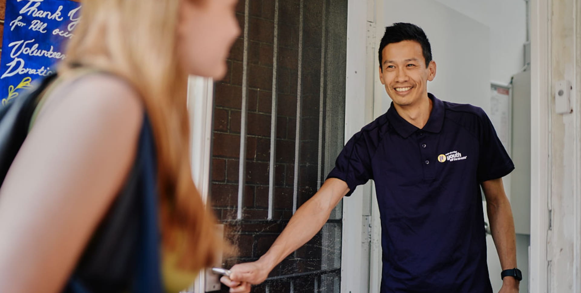 Male youth worker welcoming a teenage girl to a refuge