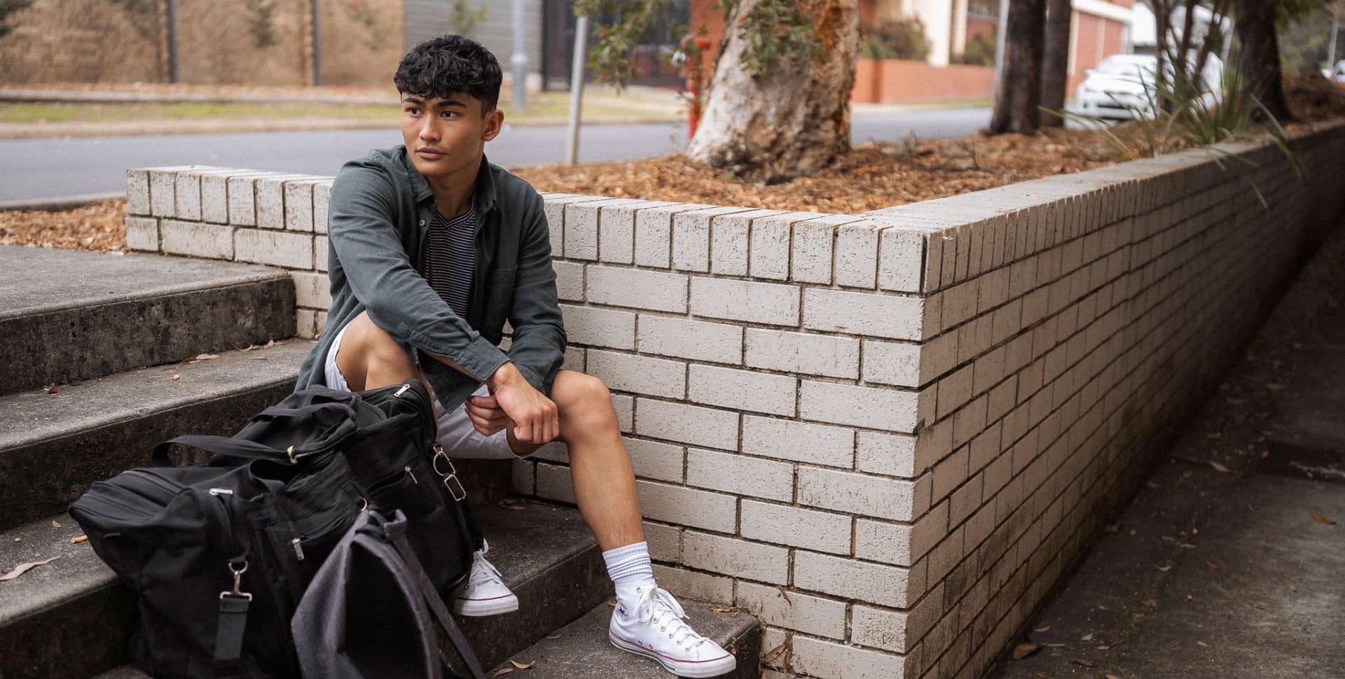 Will sitting by a brick wall with his backpack