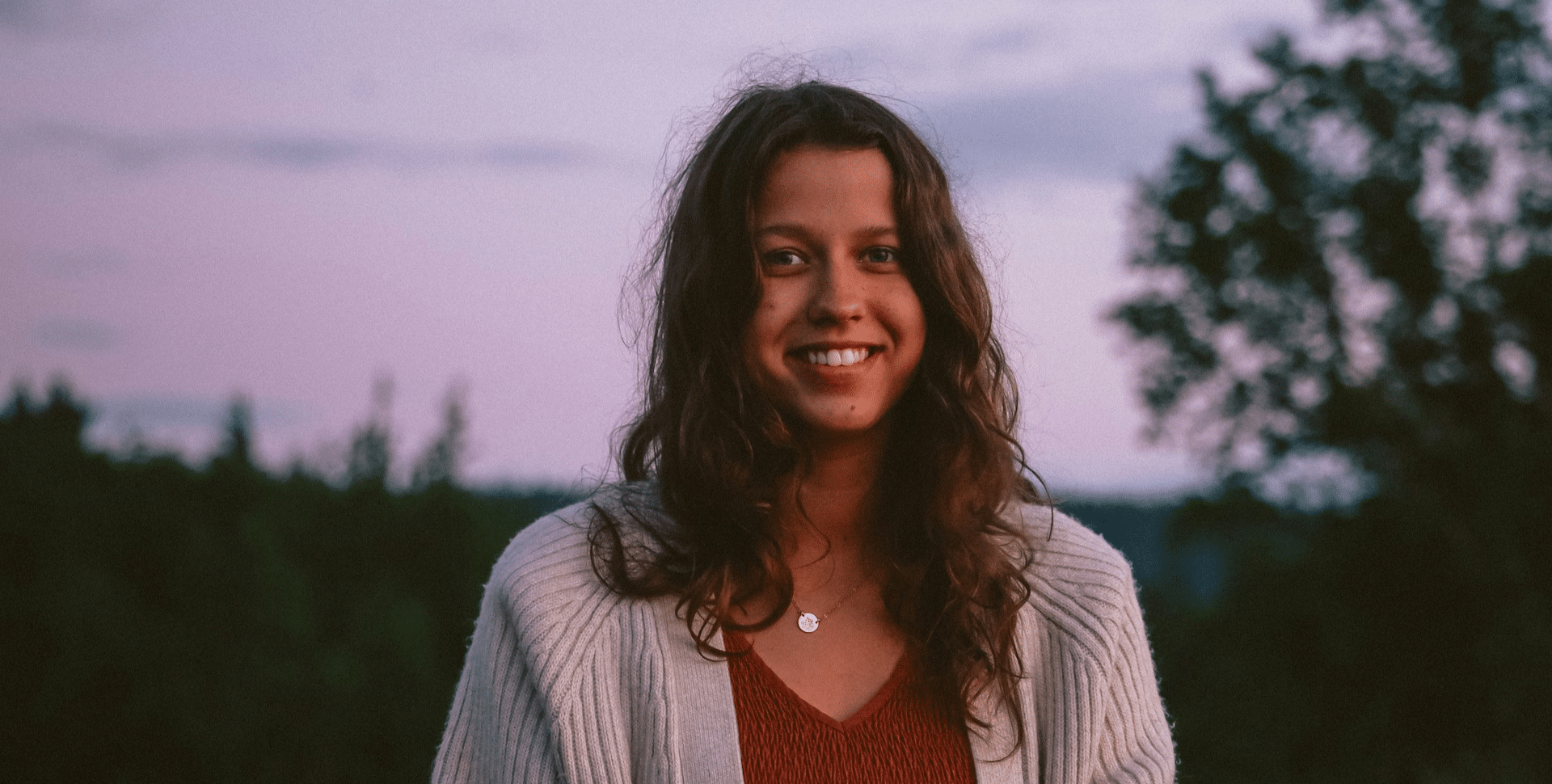A teenage girl with curly hair smiling at the camera.