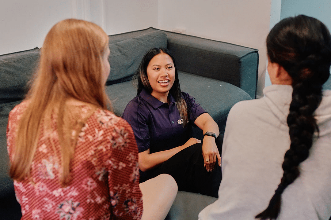A youth worker chats with two young people staying at Youth Off The Streets youth homelessness support service.