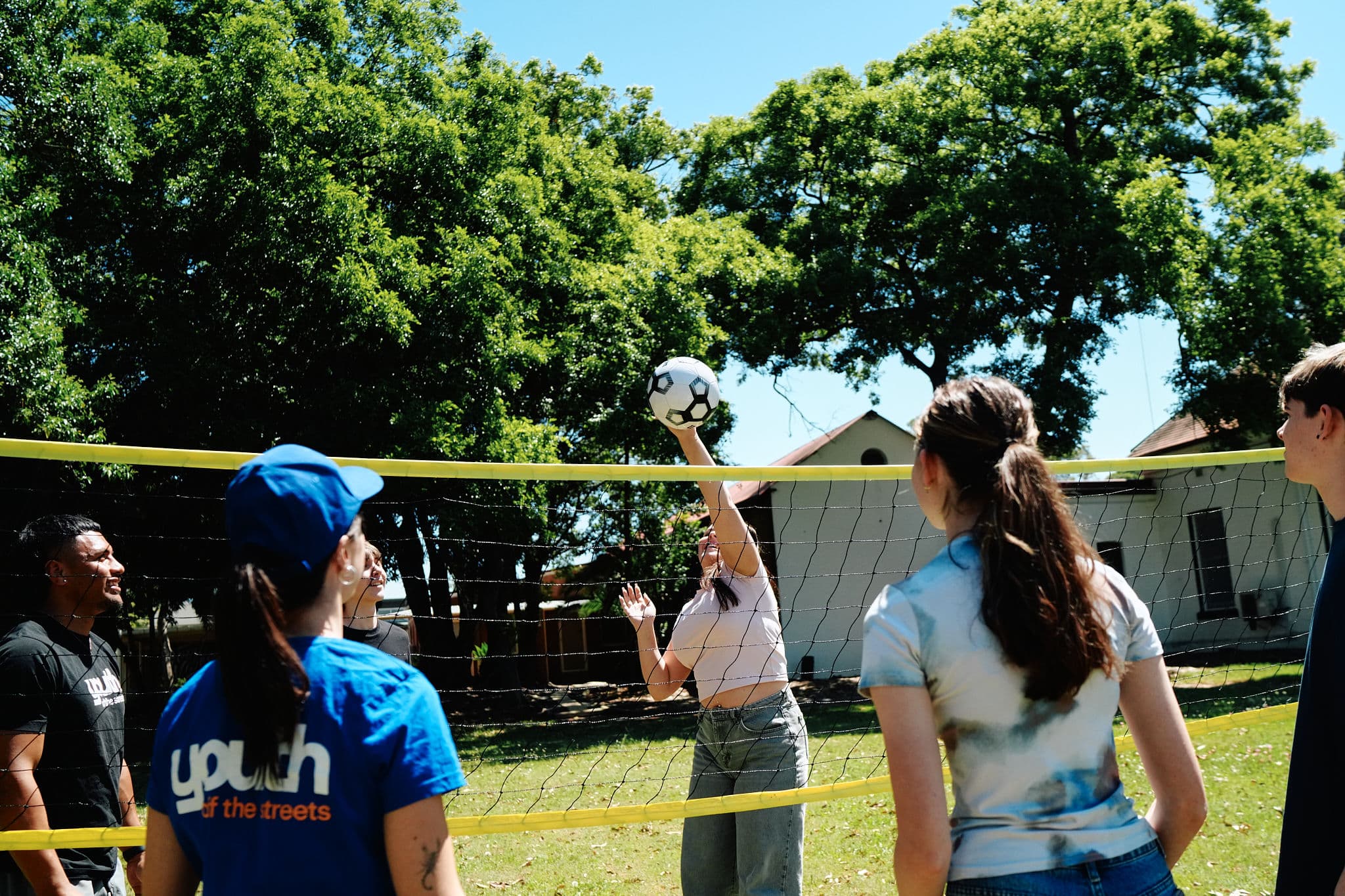 Staff and young people playing volleyball and sports at an outreach event