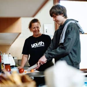 Young person learning cooking and other life skills from a Youth Off The Streets Youth Support Worker
